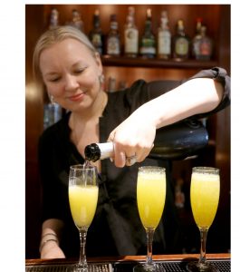 Bartender pouring mimosas at the bar.